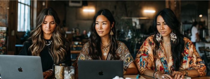 Three Native women entrepreneurs working together on laptops, building online businesses
